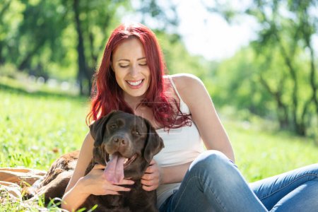Photo for "Young attractive woman hugs her dog in the park." - Royalty Free Image