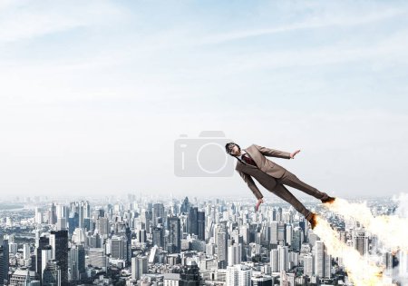 Téléchargez les photos : "Homme d'affaires en costume et chapeau d'aviateur volant dans le ciel" - en image libre de droit