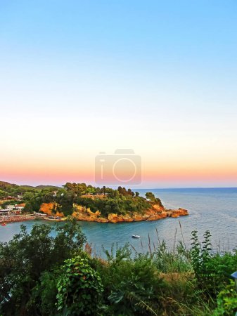 Photo for "Resort town on the coast of Montenegro. Cove with boats on the Adriatic Sea, a small tourist town with beaches. Tourist trips, swimming in the sea with boats and buoys. Sanatoria casino and bouzas" - Royalty Free Image