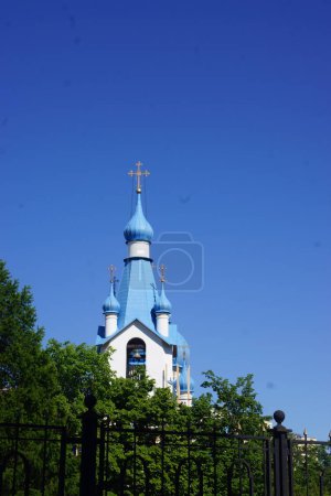Photo for "Old church Steeple spire and chimney tops against blue sky" - Royalty Free Image