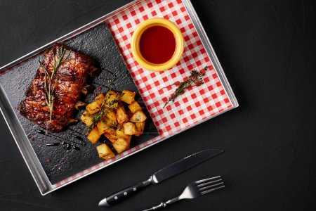 Téléchargez les photos : "Côtes grillées avec pommes de terre cuites au four et sauce chili piquante
" - en image libre de droit