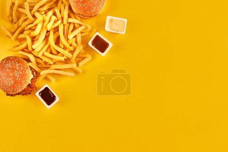 Foto de "Concepto de comida rápida con restaurante frito grasiento sacar como aros de cebolla, hamburguesa, pollo frito y papas fritas como símbolo de la tentación de la dieta que resulta en una nutrición poco saludable." - Imagen libre de derechos