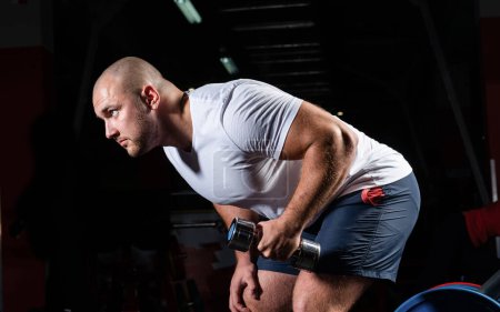 Téléchargez les photos : "bodybuilder masculin engagé avec haltères dans la salle de gym" - en image libre de droit