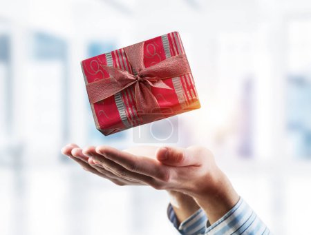 Téléchargez les photos : "Concept de Noël ou célébration avec boîte cadeau dans les paumes des hommes. Techniques mixtes" - en image libre de droit
