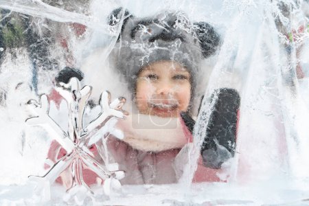 Foto de "niña con sombrero de punto y bufanda posando con esculturas de hielo" - Imagen libre de derechos