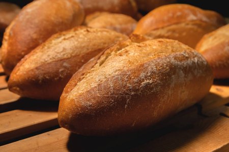 Téléchargez les photos : "Pain artisanal frais croustillant chaud et délicieux. De nombreux pains reposent sur une palette en bois" - en image libre de droit