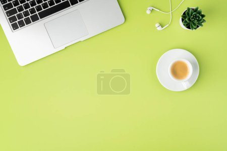 Foto de Horizontal de teclado metálico portátil, auriculares blancos y taza de café sobre fondo verde claro - Imagen libre de derechos