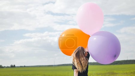 Foto de "Chica feliz con grandes globos multicolores posando en el campo." - Imagen libre de derechos