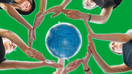 Foto de "Las colegialas abrazan el globo terráqueo con sus manos, haciendo un círculo de ellas sobre un fondo verde." - Imagen libre de derechos