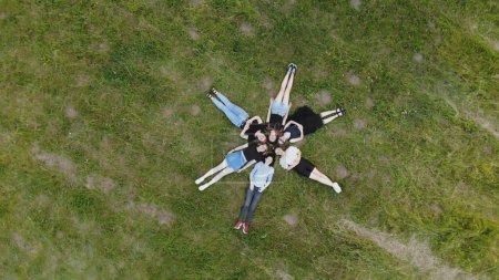 Téléchargez les photos : Les filles amies s'allongent sur l'herbe comme une fleur. - en image libre de droit