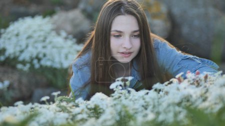 Photo for "Long-haired girl sniffs white flowers and smiles." - Royalty Free Image