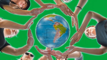 Téléchargez les photos : Les écolières embrassent le globe terrestre avec leurs mains, en faisant un cercle sur un fond vert. - en image libre de droit