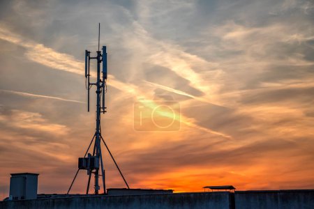 Téléchargez les photos : "silhouette des émetteurs GSM sur le toit de l'immeuble de bureaux à nuages étonnants
" - en image libre de droit