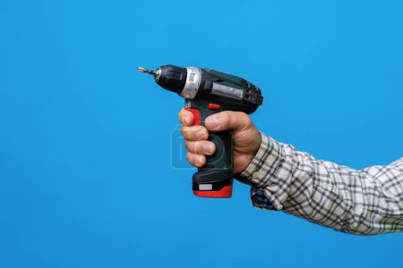 Photo for "Male hand holding screwdriver against blue background" - Royalty Free Image