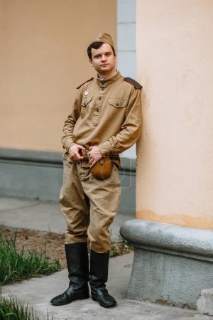 Foto de Un hombre con uniforme soviético de la Segunda Guerra Mundial está en la pared amarilla - Imagen libre de derechos