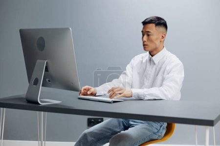 Téléchargez les photos : Travailleur assis à un bureau devant un ordinateur isolé arrière-plan - en image libre de droit