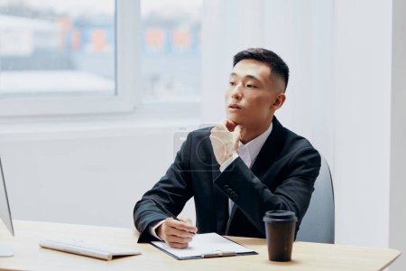 Téléchargez les photos : Homme en costume verre de café assis à une table en face d'une technologie informatique - en image libre de droit