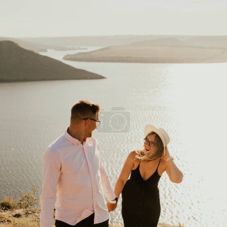 Photo for "man and woman in love walk on a mountain above a large lake sea" - Royalty Free Image