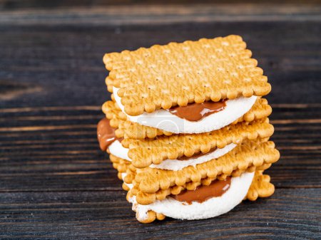 Photo for "Smores, marshmallow sandwiches - traditional American sweet chocolate cookies on dark wooden table, side view" - Royalty Free Image