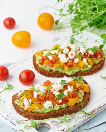 Photo for "avocado toast with feta and tomatoes, smorrebrod with ricotta, closeup and vertical" - Royalty Free Image