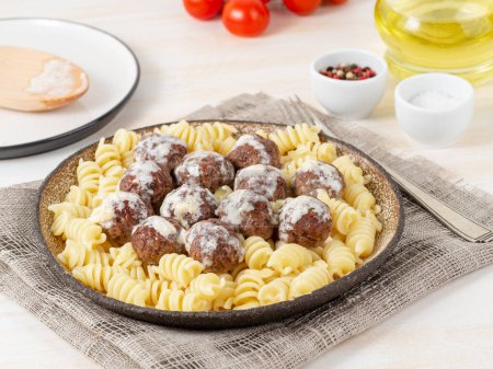 Photo for "Swedish meatballs with sauce and fusilli paste on white wooden table, side view" - Royalty Free Image