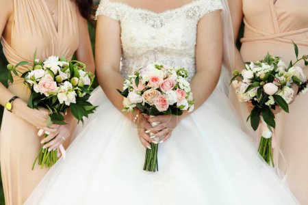 Téléchargez les photos : "Mariée et demoiselles d'honneur tenant avec des bouquets de mariage dans leurs mains" - en image libre de droit