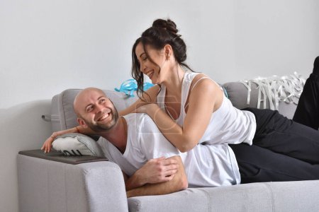 Photo for "Family couple smiling and hugging sitting on sofa" - Royalty Free Image
