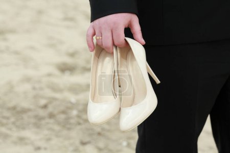 Téléchargez les photos : "Belles chaussures de mariage dans les mains de fiancé" - en image libre de droit