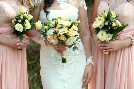 Photo for "Bride and bridesmaids holding with wedding bouquets on their hands" - Royalty Free Image