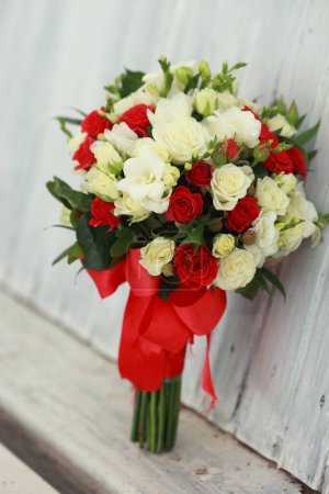 Téléchargez les photos : "vue du haut du bouquet de luxe de fleurs rouges et blanches sur bois .top vue avec arc rouge le jour du mariage vacances" - en image libre de droit