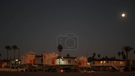 Téléchargez les photos : "Palmiers et lune dans le ciel crépusculaire, sauveteur de côte de Californie, maisons de plage." - en image libre de droit