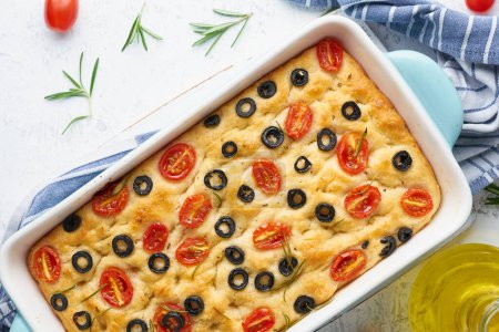 Téléchargez les photos : "Focaccia aux tomates, olives et romarin en cocotte, vue sur le dessus. Pain plat italien traditionnel" - en image libre de droit