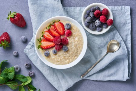 Photo for Oatmeal with blueberries, strawberries, raspberries on blue dark background - Royalty Free Image