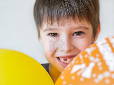 Photo for Smiling kid shows hole in row of teeth in his mouth. One incisor fell out just now. Happy child with air balloons. - Royalty Free Image