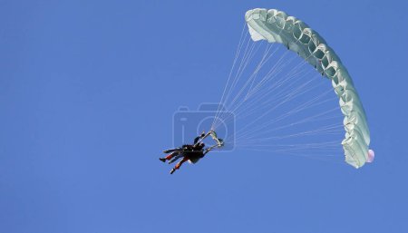 Photo for A skydiver with a white parachute canopy against a blue sky and white clouds, close-up. - Royalty Free Image