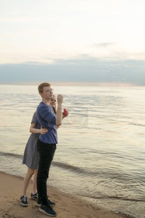 Téléchargez les photos : Adolescent couple soufflant bulles de soupe sur l 'plage - en image libre de droit