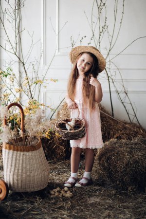 Photo for Little lovely kid in peachy dress and hat posing at camera. - Royalty Free Image