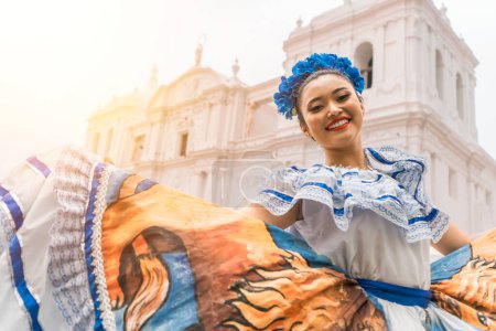 Téléchargez les photos : Danseuse folklorique nicaraguayenne souriant et regardant la caméra devant l'église cathédrale dans le parc central de la ville de Léon. La femme porte la robe typique de l'Amérique centrale et similaire aux pays d'Amérique du Sud - en image libre de droit