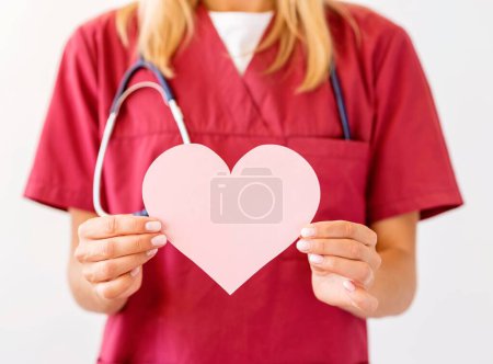 Téléchargez les photos : Vue de face du médecin féminin avec stéthoscope tenant le coeur en papier - en image libre de droit
