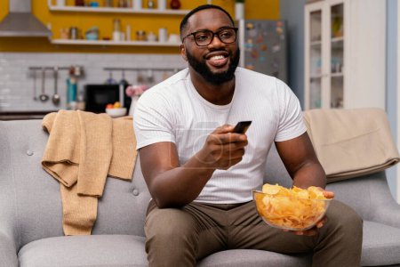 Photo for Man watching tv eating chips - Royalty Free Image