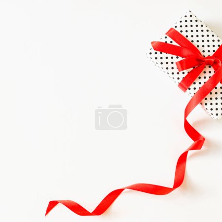 Foto de Regalo vista elevada atado con cinta roja superficie blanca - Imagen libre de derechos