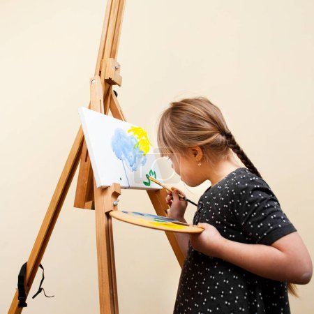 Photo for Side view of girl with down syndrome painting with brush - Royalty Free Image