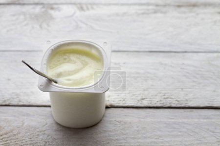 Photo for "Yogurt and spoon on wooden table" - Royalty Free Image