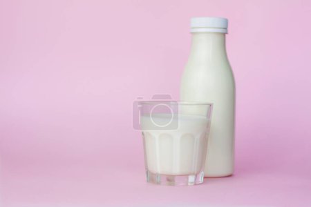 Foto de "Una botella y un vaso de leche blanca, resaltado sobre un fondo rosa, primer plano. " - Imagen libre de derechos
