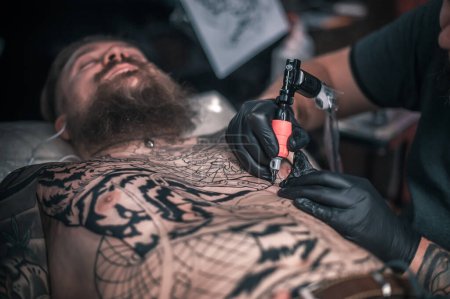 Téléchargez les photos : "Tatoueur fait tatouage cool dans le salon" - en image libre de droit