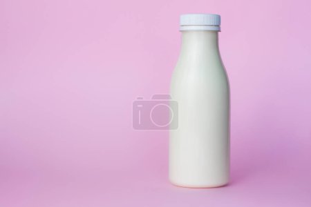 Téléchargez les photos : "Une bouteille de lait blanc, surlignée sur fond rose, gros plan. " - en image libre de droit