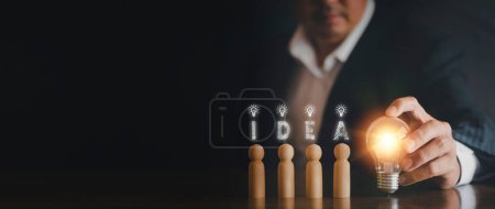 Photo for "Hand man holding light bulb with text i d e a and wooden doll. Innovation idea and knowledge concept. Hand of businessman holding light bulb with wooden doll" - Royalty Free Image