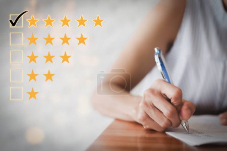 Photo for "Female hand using a pen to fill out a questionnaire. Customer satisfaction questionnaire. Five star rating. Check the box for five stars. positive emotions customer feedback" - Royalty Free Image