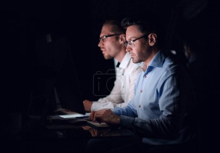 Photo for Two colleagues sitting at the Desk.isolated on black - Royalty Free Image