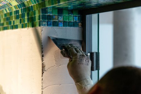 Foto de "Trabajador aplicando azulejos de mosaico, baño o sauna renovación" - Imagen libre de derechos